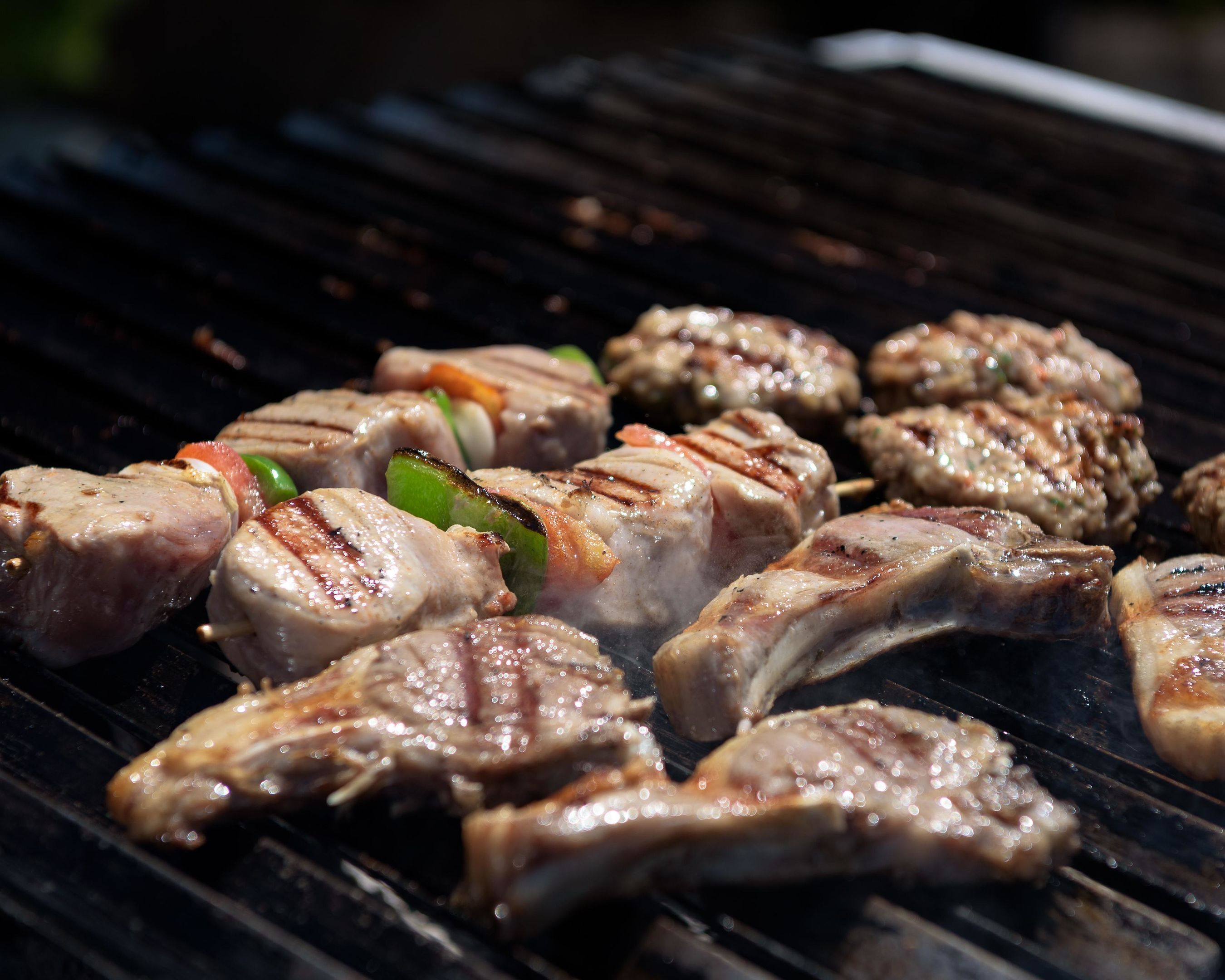 Una parrilla con diversos tipos de carne y verduras asándose.