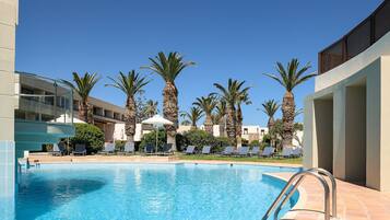 A swimming pool with lounge chairs and palm trees.