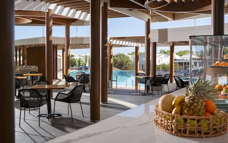 An outdoor seating area with tables and chairs, a pool, and a fruit basket.
