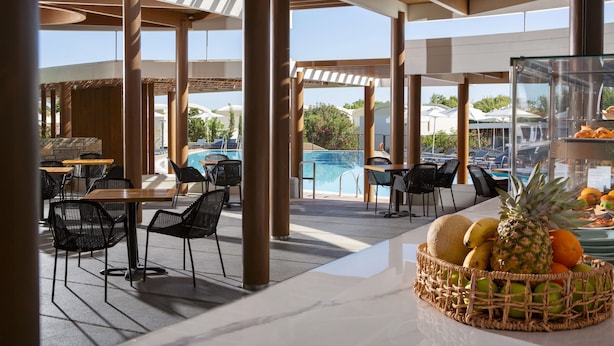 An outdoor seating area with tables and chairs, a pool, and a fruit basket.