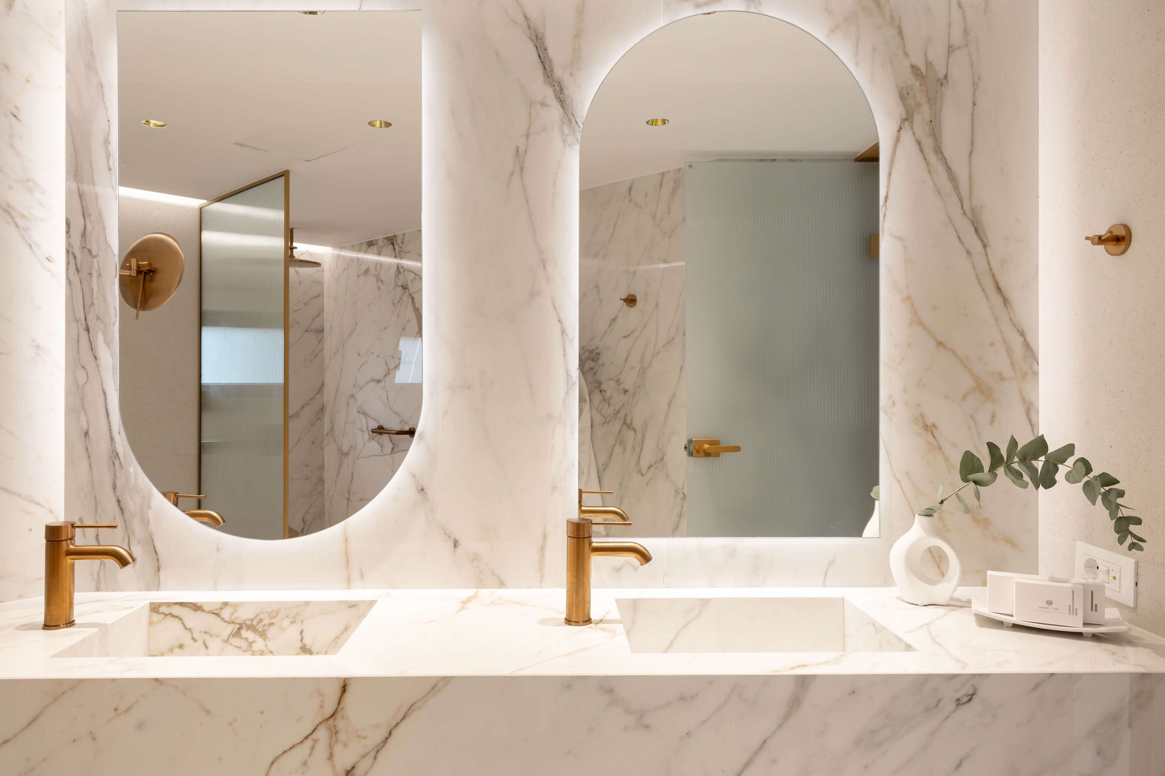 Une salle de bain avec deux lavabos, des murs en marbre et un grand miroir.