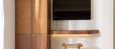 A modern room with a wooden cabinet, a mounted TV, and a woven chair.