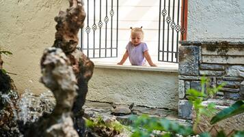 A child looking out from a window with metal bars.