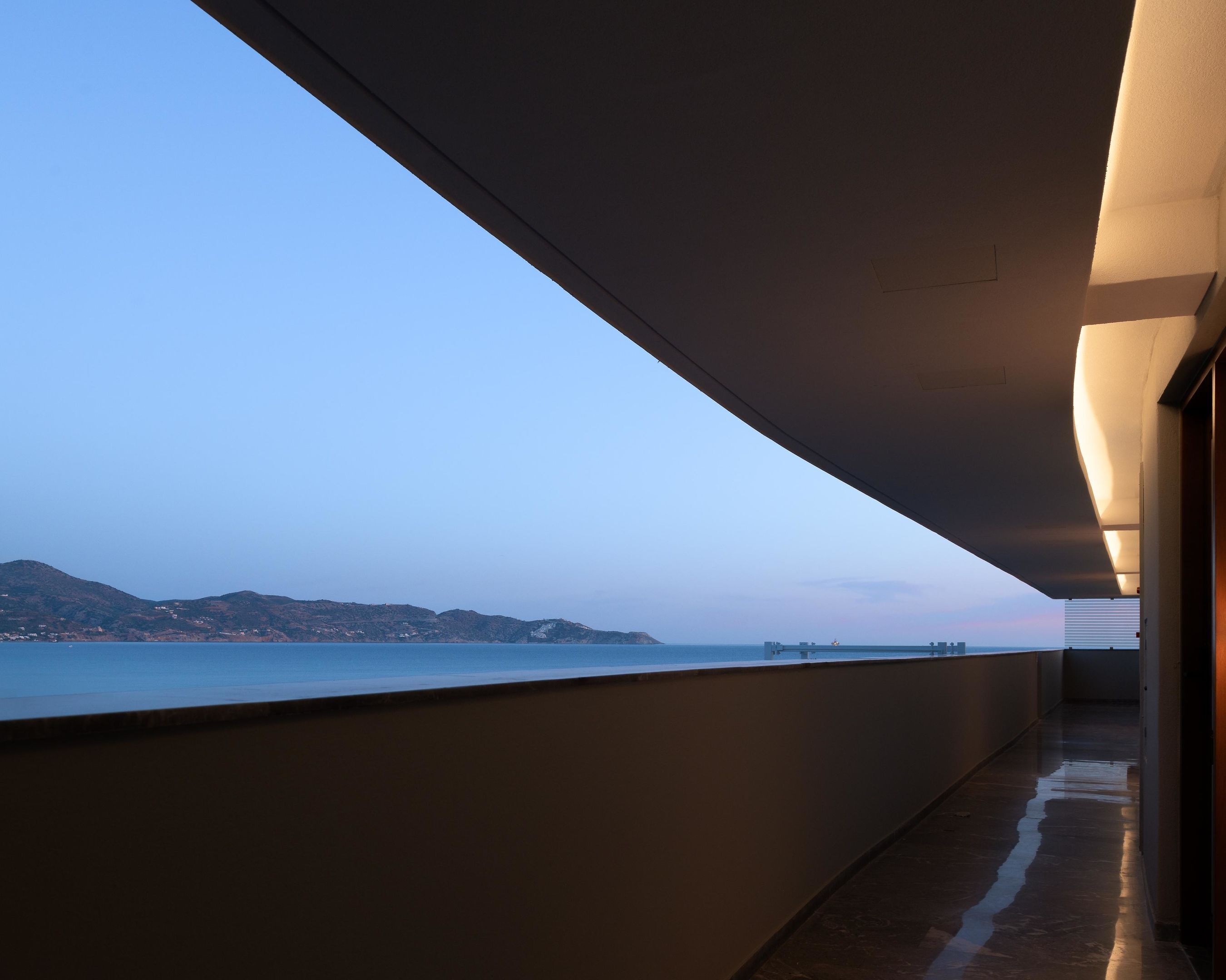 A corridor with a view of the sea and distant hills.