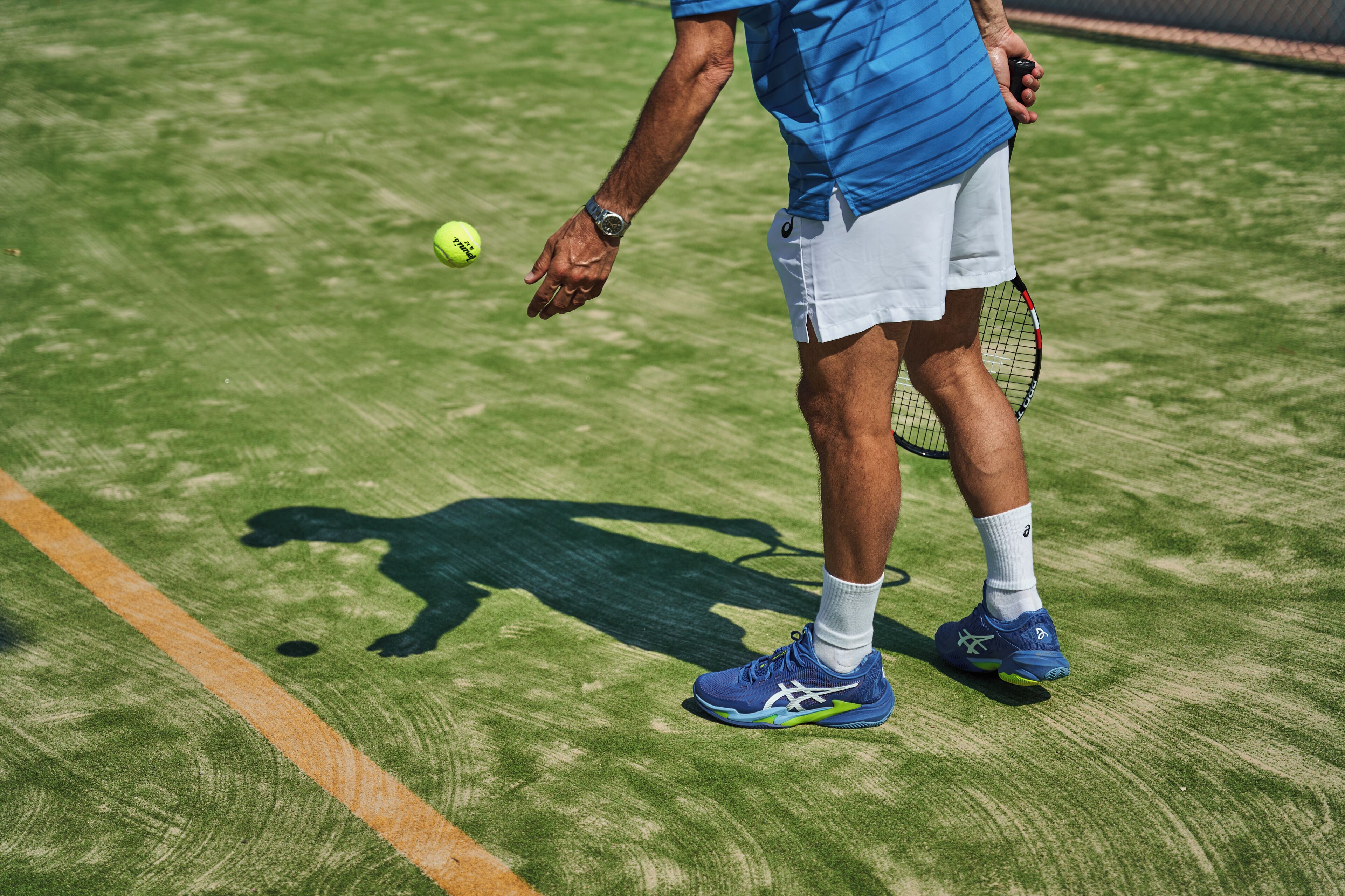 Una cancha de tenis con un jugador sosteniendo una raqueta y una pelota.