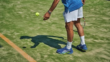 Una cancha de tenis con un jugador sosteniendo una raqueta y una pelota.