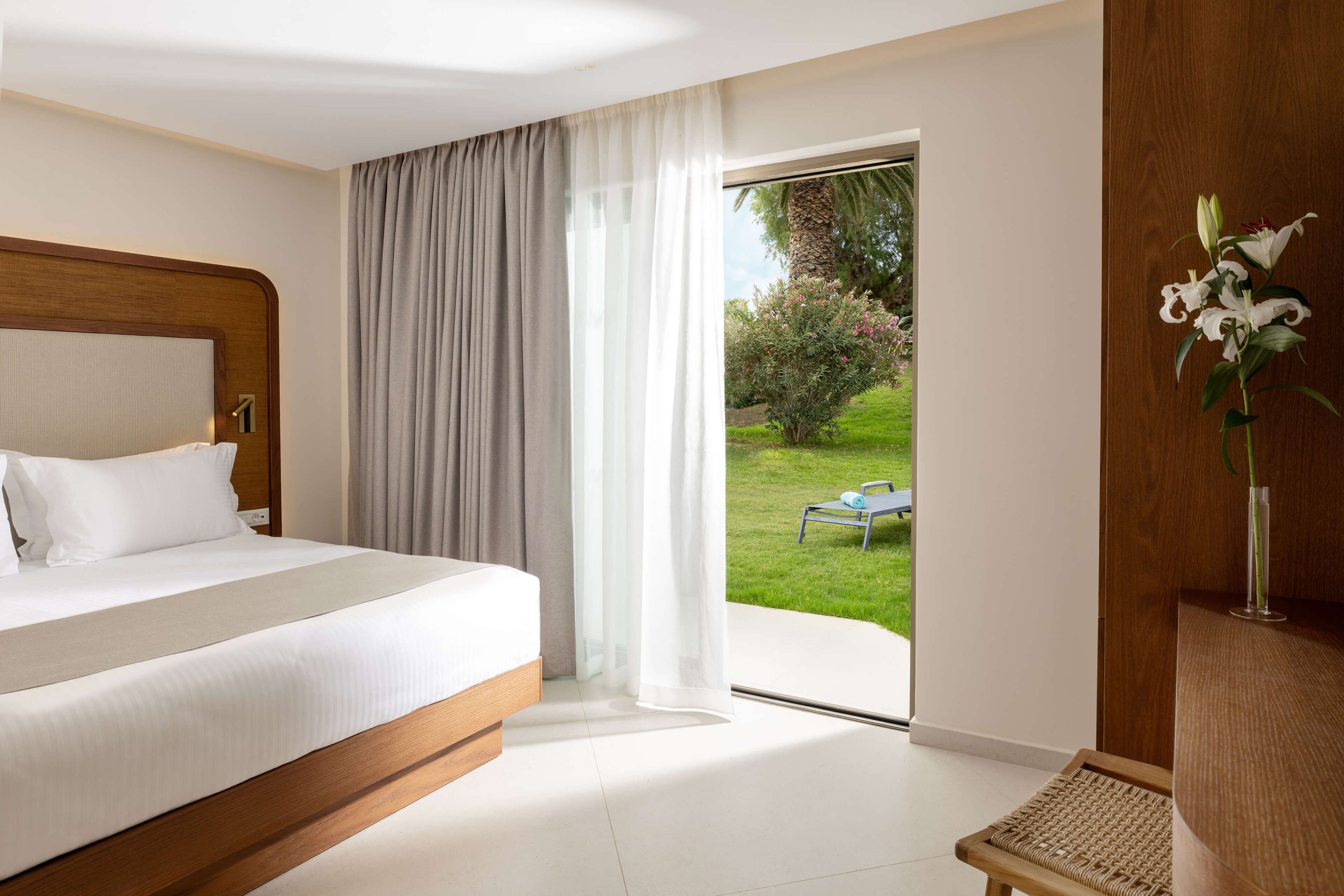 A hotel room with a bed, a view of the garden, and a chair.