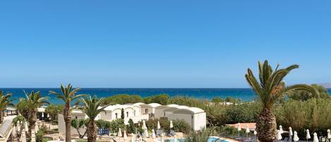 A resort with a pool, palm trees, and a view of the sea.