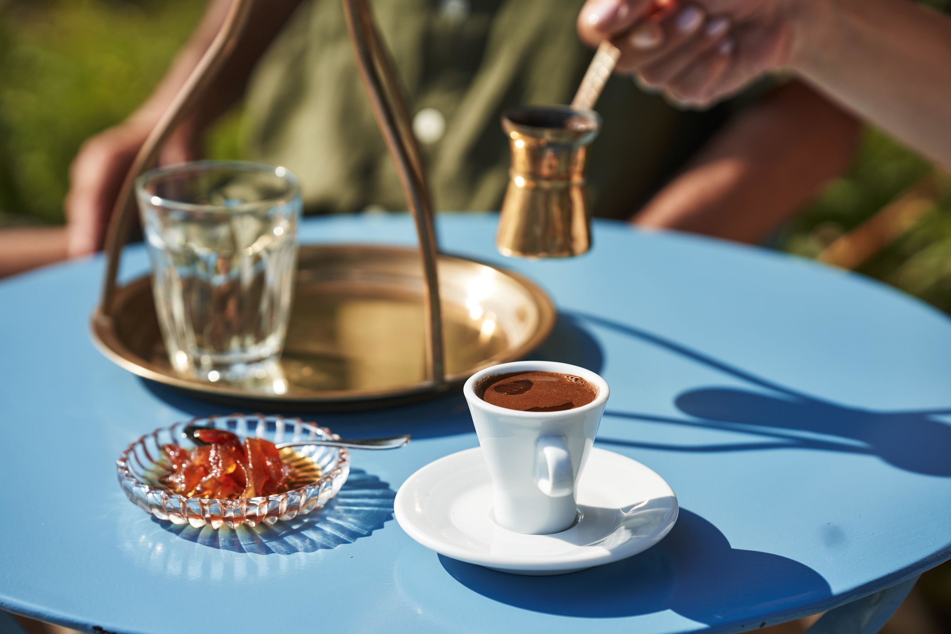 Una mesa con una taza de café, un vaso de agua y una bandeja con una pipa de agua.