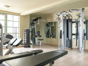 A gym with exercise equipment, a bench, and a mirror.