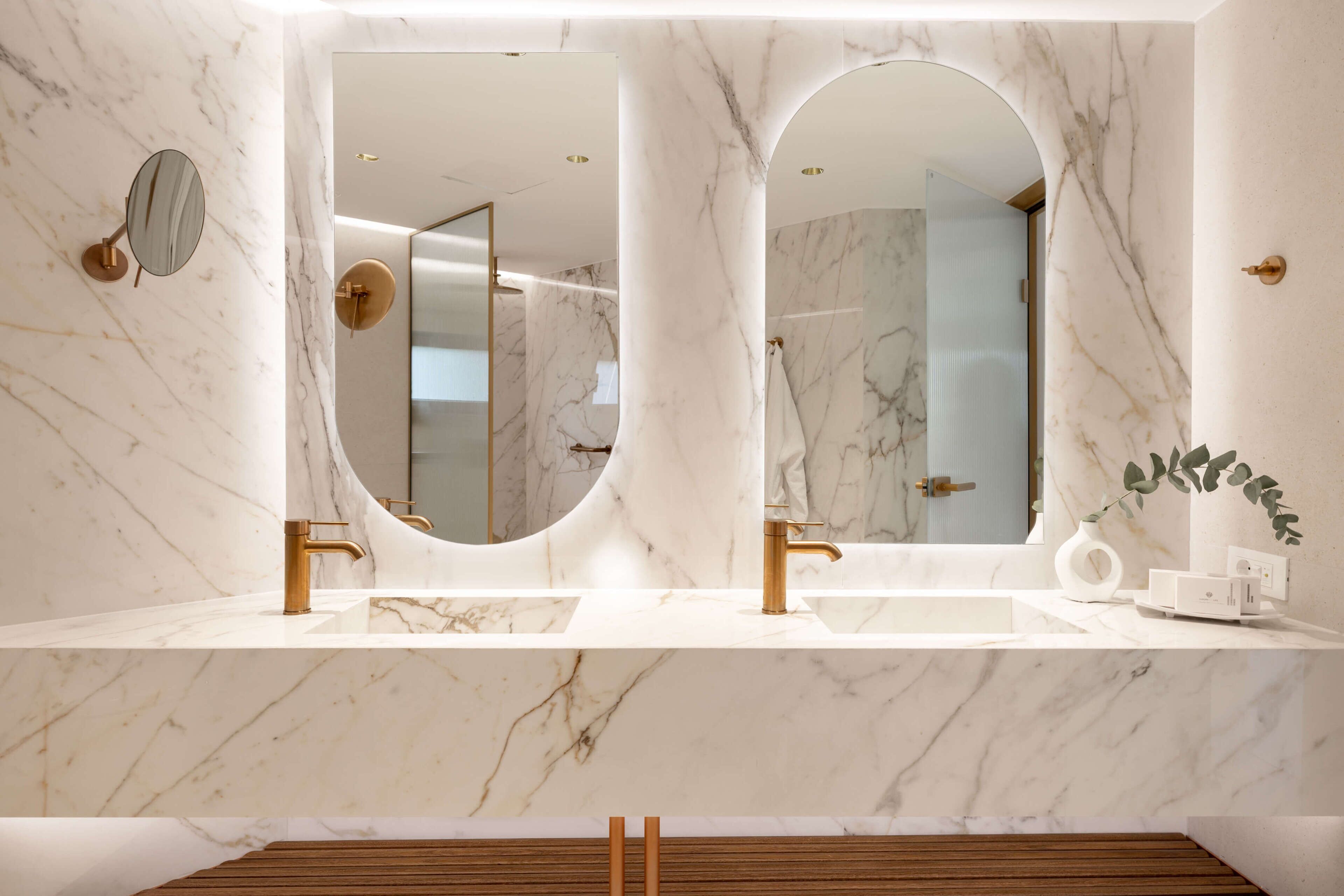Un baño con dos lavamanos, espejos grandes y piso de madera.