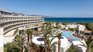 A resort with a pool, palm trees, and a view of the sea.