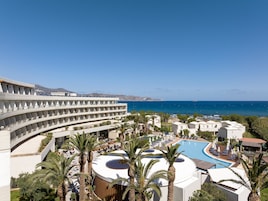 Un resort con piscina, palmeras y vistas al mar.
