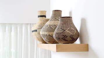 Three woven vases on a wooden shelf against a white wall.
