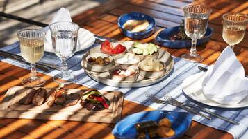 A table set with various dishes, glasses of white wine, and a blue bowl.