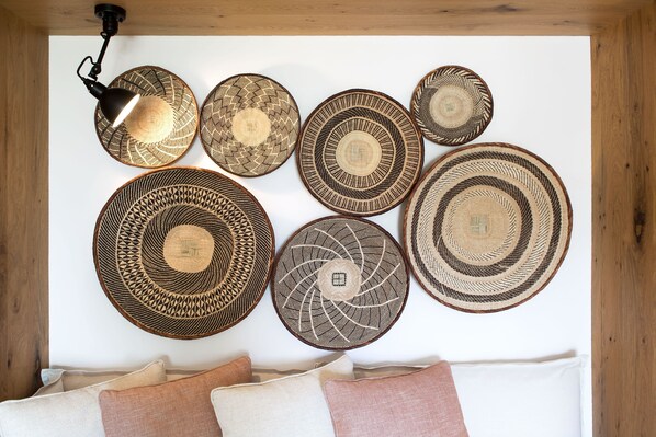 A wall with several woven baskets and a hanging lamp.