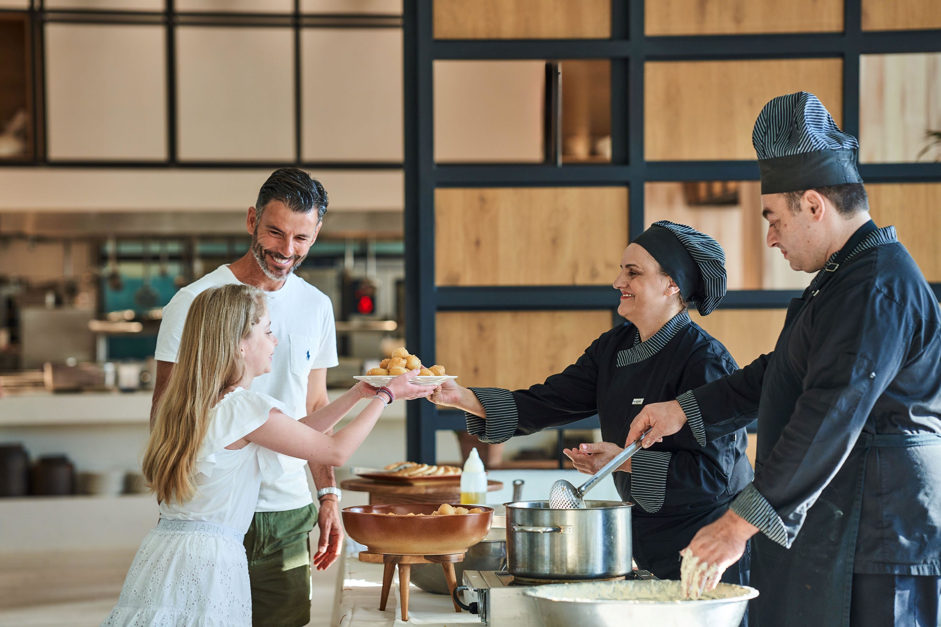 A buffet setup with a large pot and a bowl of food, a person serving food, and another person receiving food.