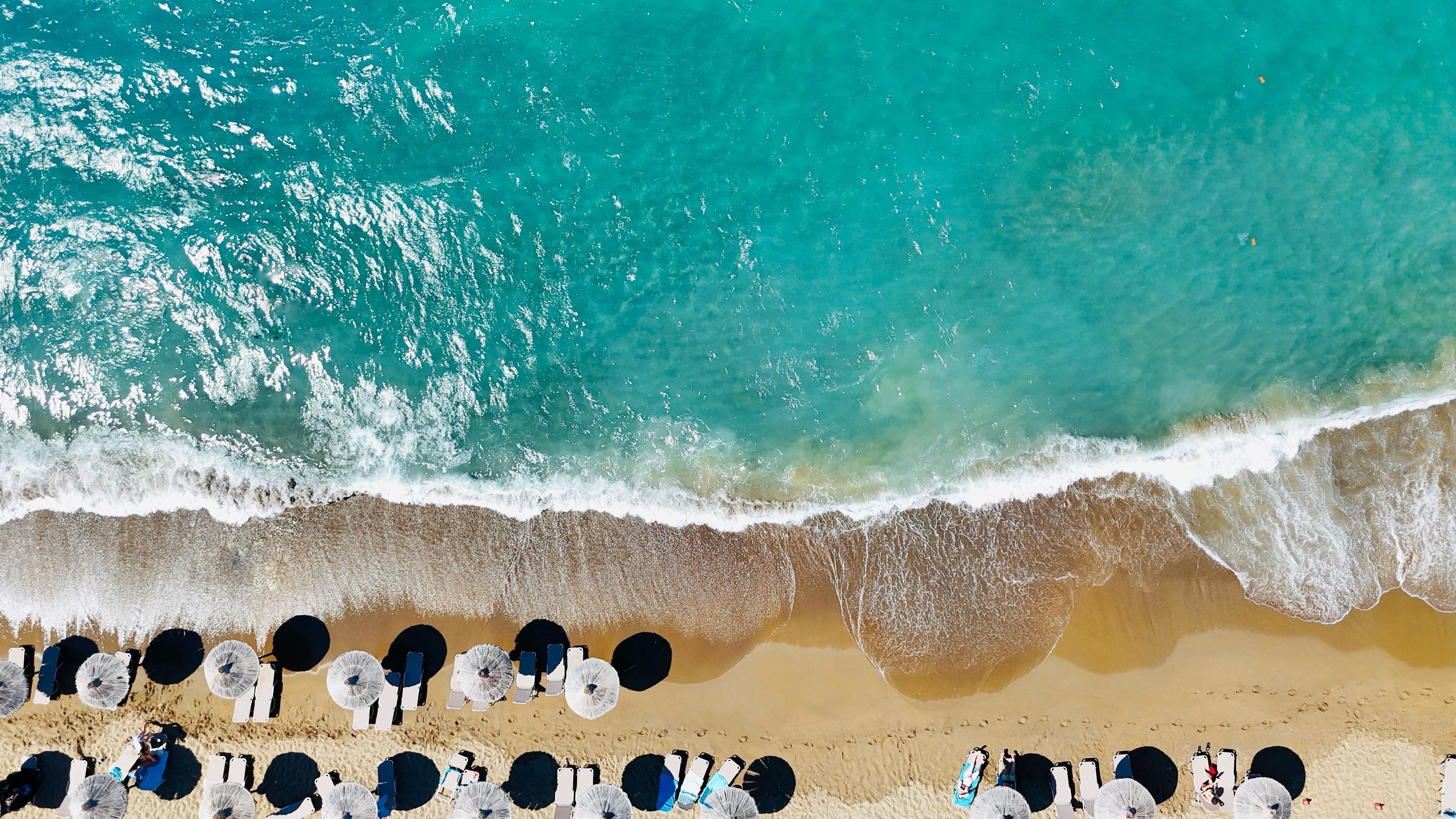 Vista aerea di una spiaggia con file di lettini e ombrelloni.