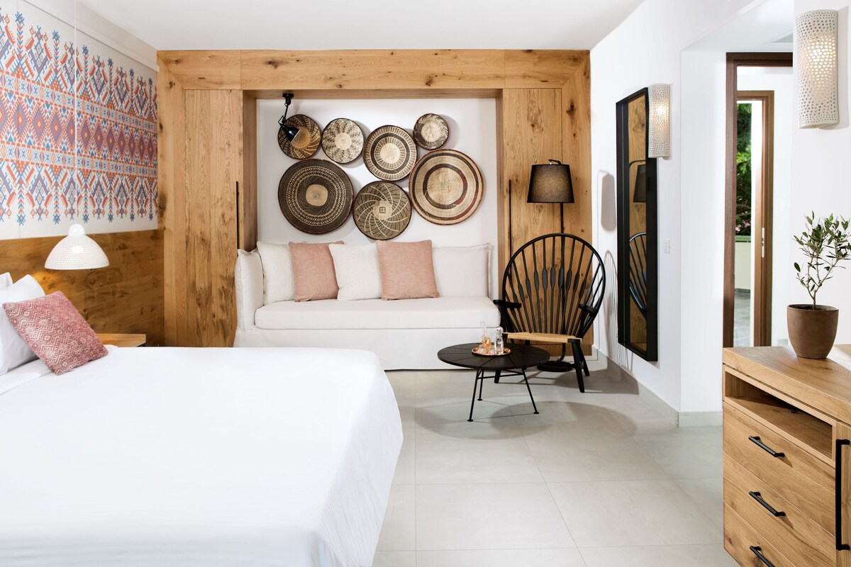 A modern room with a white sofa, a wooden cabinet, a round table, and a wall decorated with circular plates.