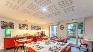 Un comedor con sillas rojas, una mesa blanca y una cocina con refrigerador y fregadero.