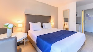 Una habitación de hotel con cama, mesitas de noche, escritorio y espejo.