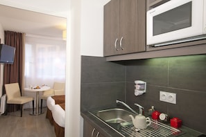 Una cocina moderna con microondas, lavabo y un pequeño comedor con mesa y sillas.
