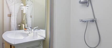 A modern bathroom with a white sink, mirror, and shower.