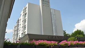 A building with a sign reading "Grand Hotel" and a row of pink flowers in front.