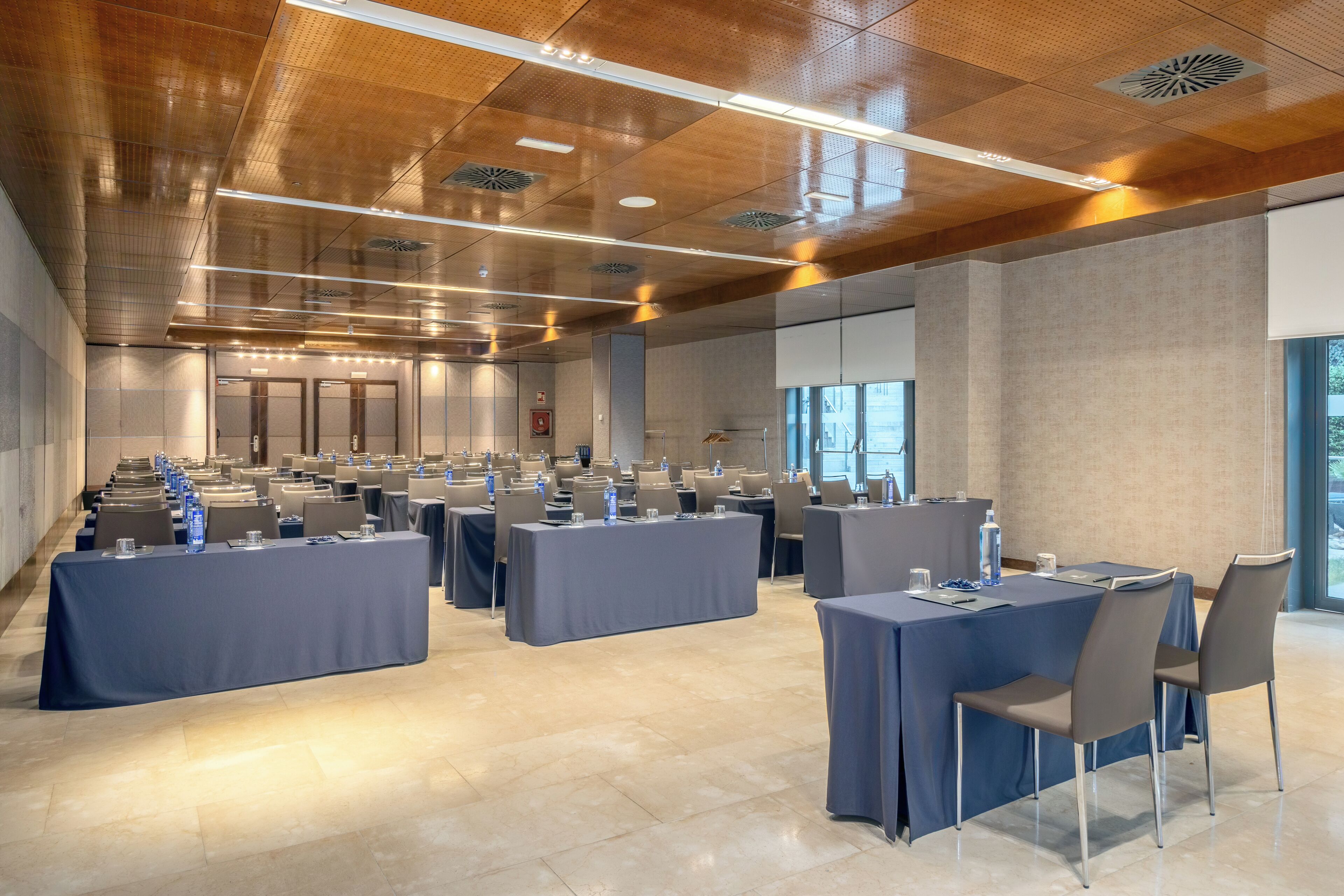 Una sala de conferències amb diverses taules i caires, grans finestres i un disseny de sostre modern.