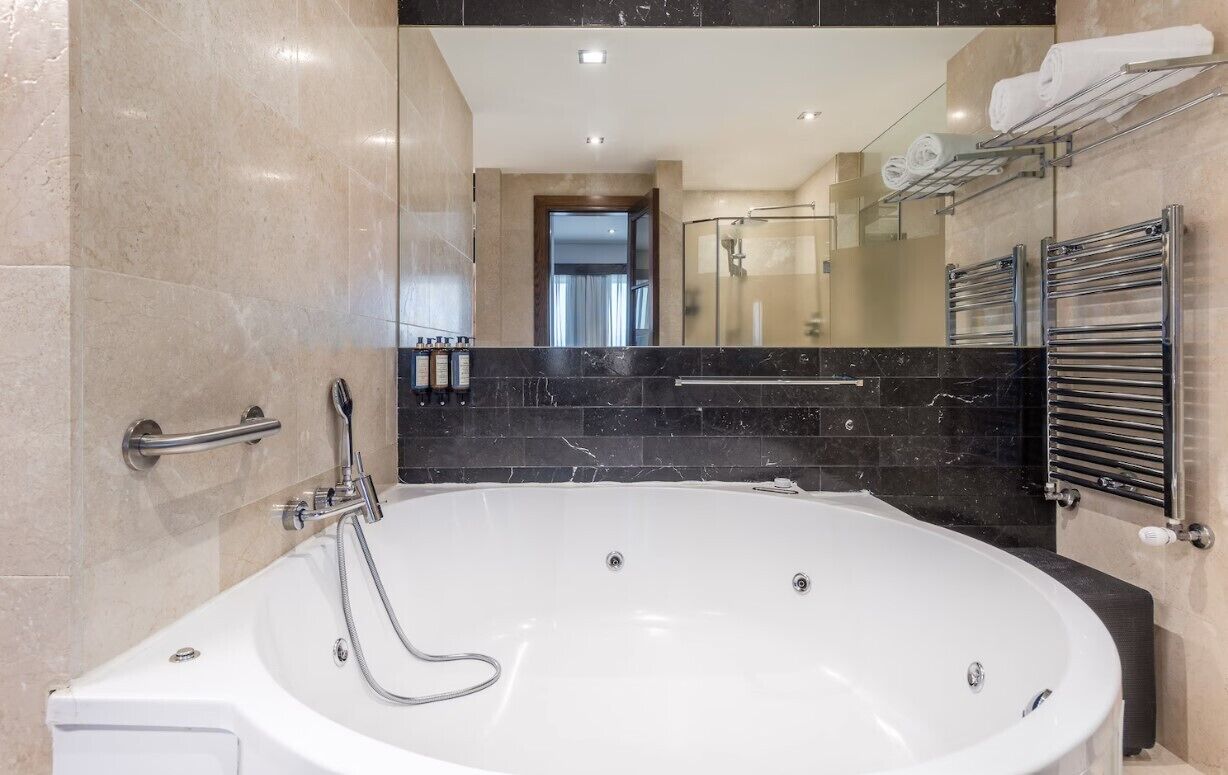A modern bathroom with a large bathtub, a glass shower enclosure, and a vanity with a mirror.