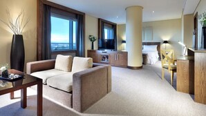 Camera d'albergo con divano, televisione, scrivania, letto e vista sulla città.