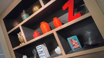 Una estantería de madera con varios objetos decorativos, incluyendo una gran letra 'Z' roja, un búho de cerámica blanca y una tarjeta azul con la palabra 'PICON'.