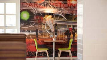 A dining area with a mural of vintage bicycles and a table with two chairs.