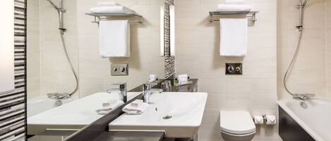 A modern bathroom with two sinks, a toilet, and a bathtub.