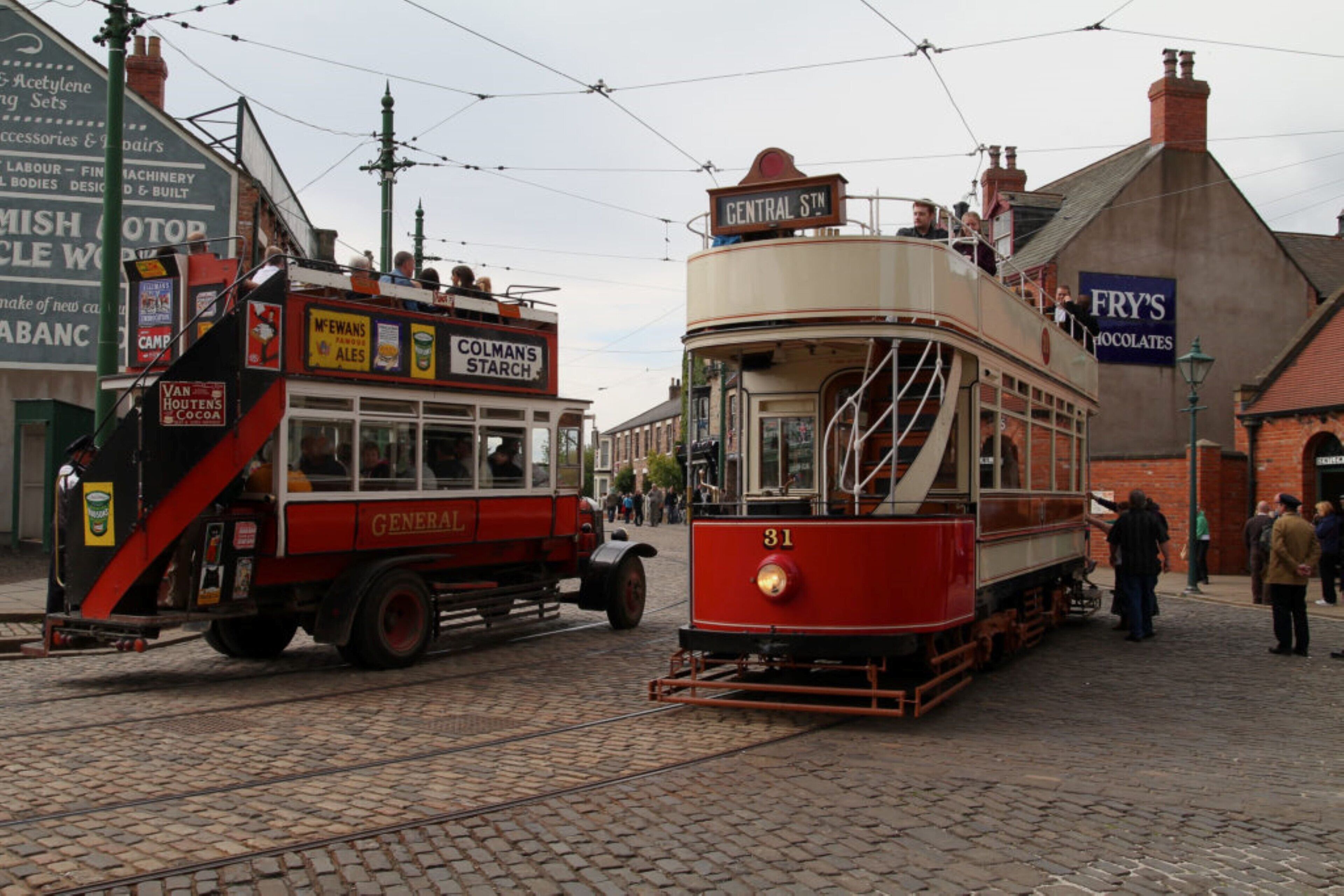 A tram with the number 31 on a cobblestone street, surrounded by buildings with various signs and advertisements.