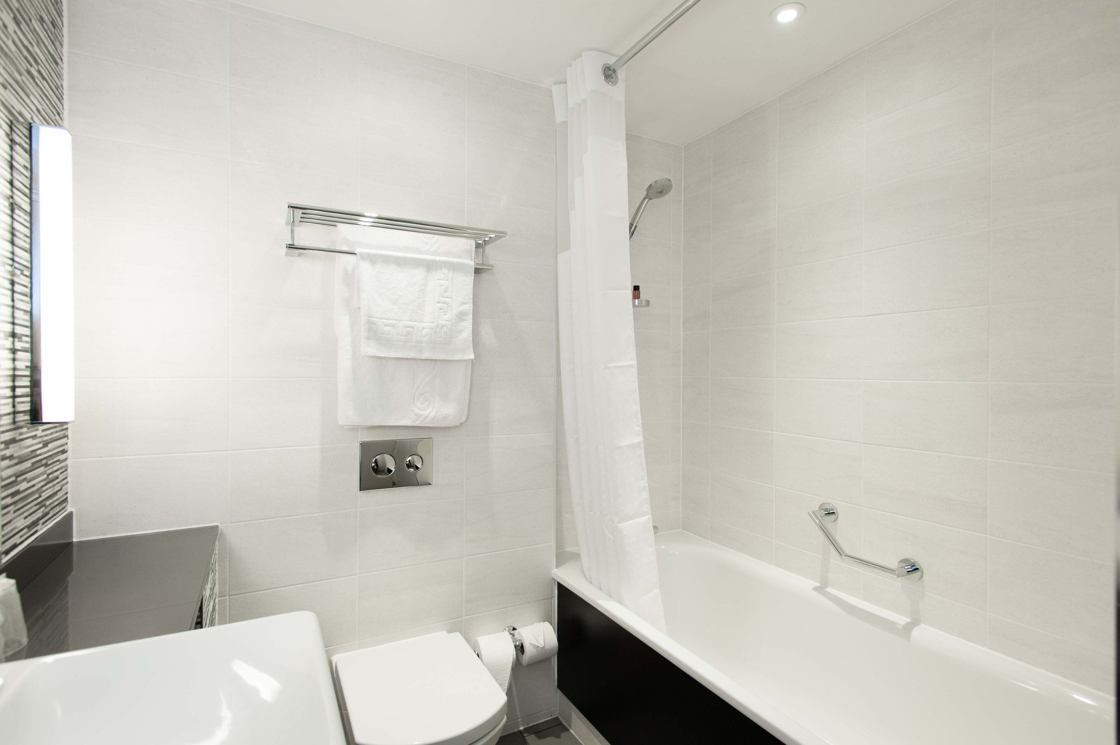 Een moderne badkamer met een wit toilet, een bad en een douchehoek.