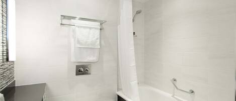A modern bathroom with a white toilet, a bathtub, and a shower area.
