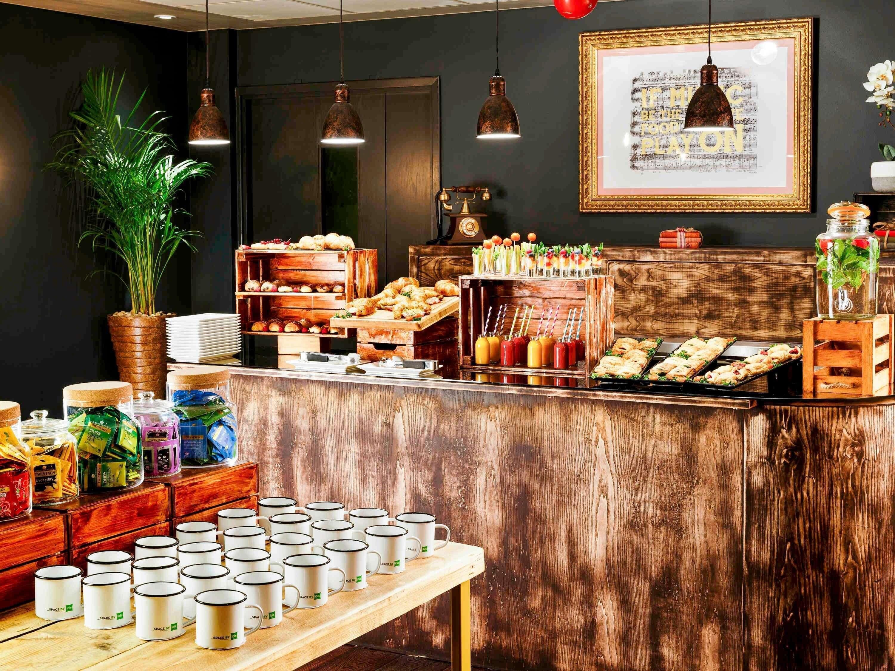 A buffet setup with various food items, a potted plant, and a framed picture on the wall.