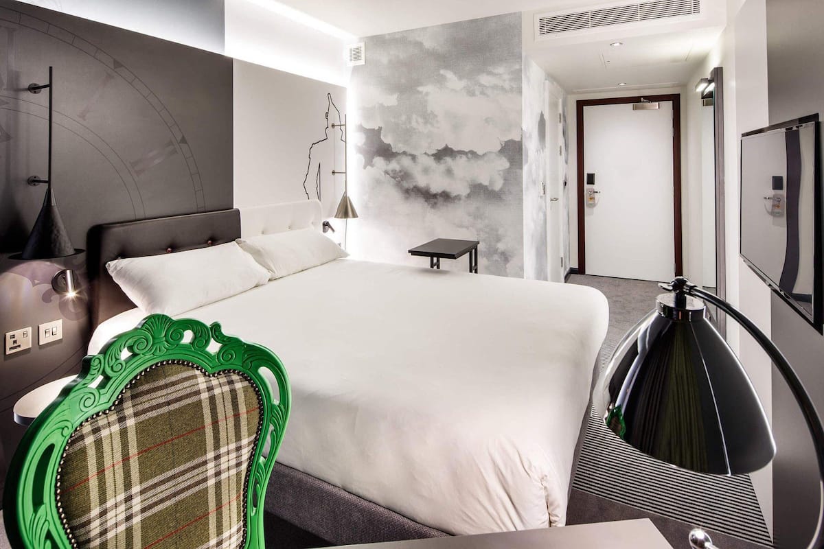 Une chambre d’hôtel moderne équipée d’un grand lit, d’un bureau, d’une chaise et d’une télévision.