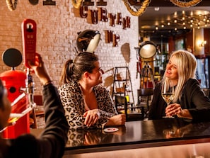 A bar area with a brick wall, a red drum set, and a sign reading 'CURE YOURSELF.' - ibis Styles London Southwark – near Borough Market (London)