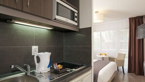 Cuina moderna amb microones, bullidor i fogó. Hi ha un rentaplat i una taula petita amb una cadira. L'habitació té un llit i una televisió.