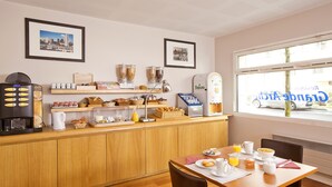 Zona de petit esmorzar amb un taulell de fusta, màquina de cafè i diferents aliments.