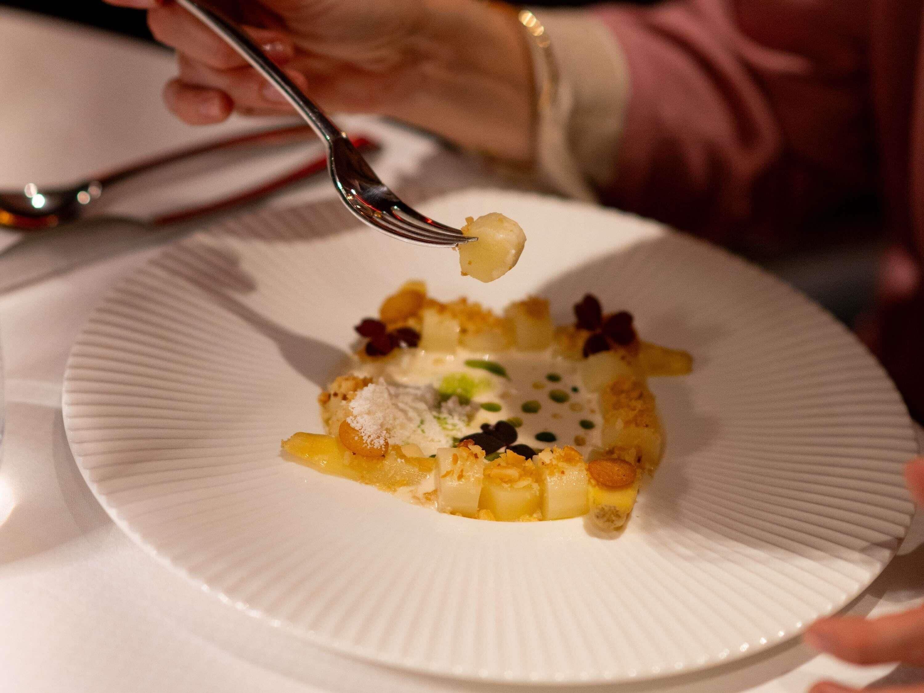 Una persona come un postre con un tenedor sobre un plato blanco.