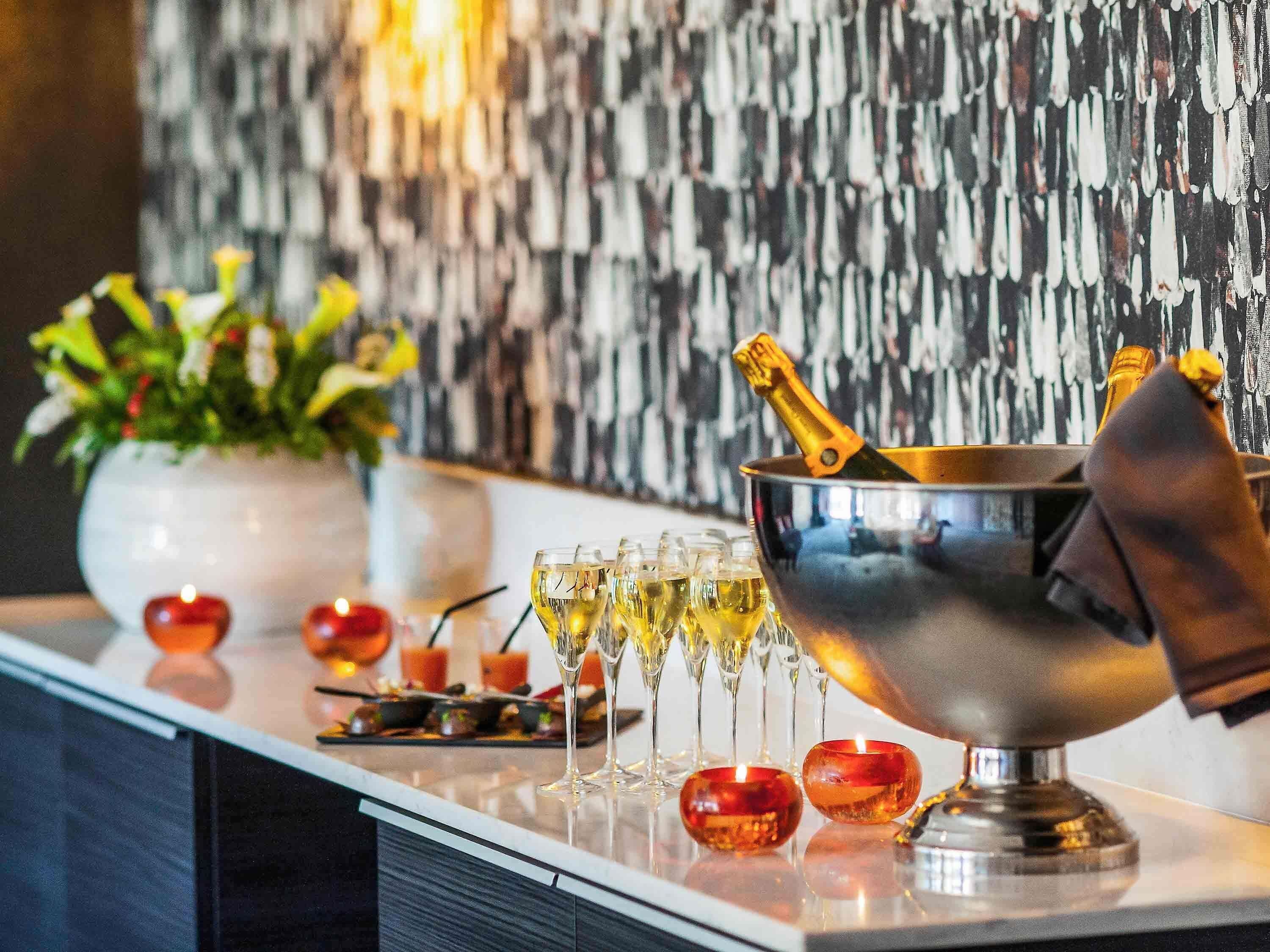 Uma área de bar com balde de champanhe, copos e objetos decorativos em um balcão.