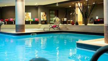 Relax by the pool with lounge chairs and a table nearby, surrounded by artwork and a potted plant.