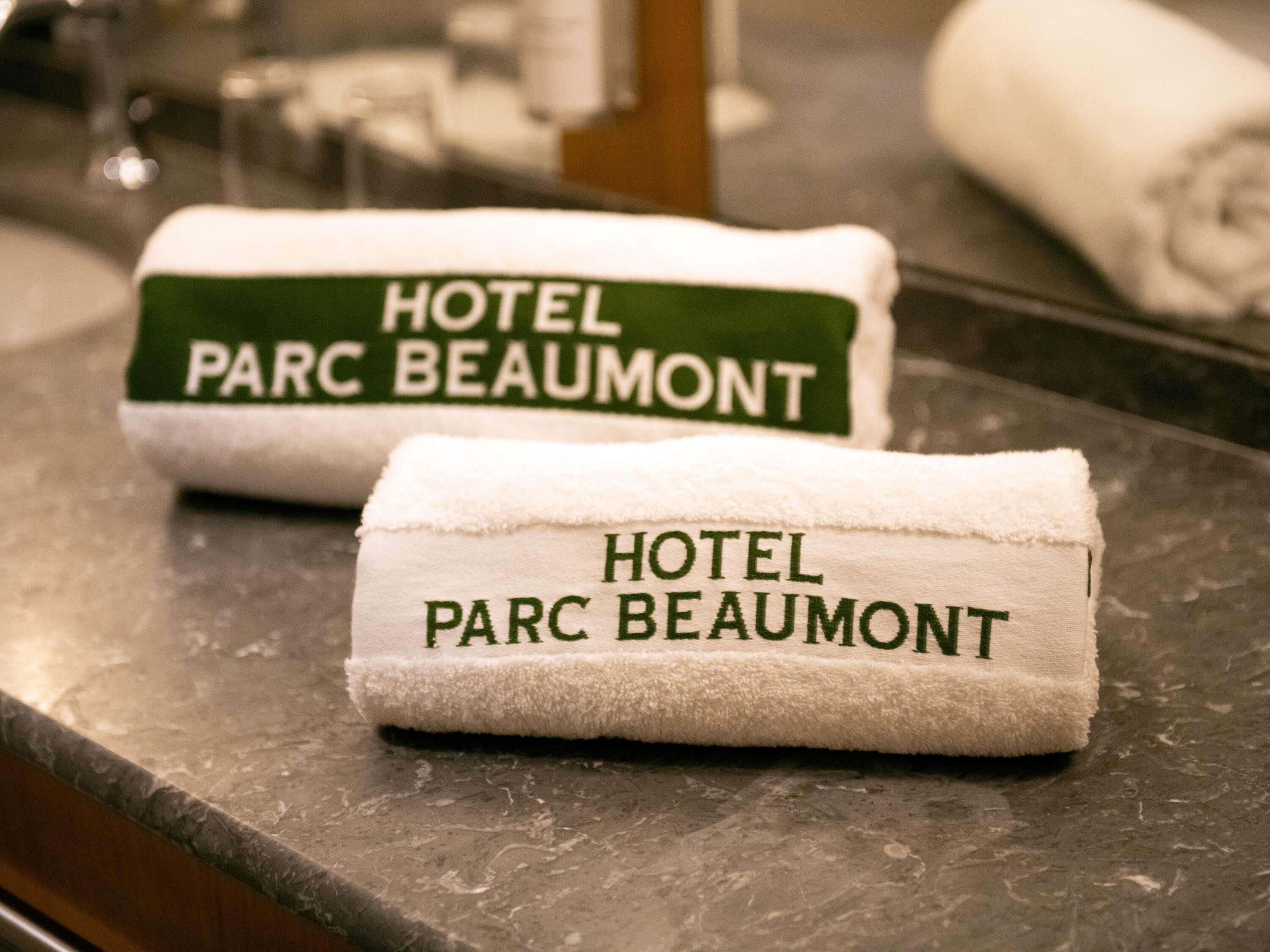 Two towels with 'HOTEL PARC BEAUMONT' printed on them, placed on a marble countertop.