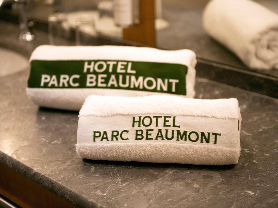 Two towels with 'HOTEL PARC BEAUMONT' printed on them, placed on a marble countertop.
