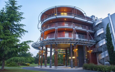 A multi-story hotel with a circular design, featuring balconies and a covered entrance area.