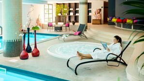 A pool area with lounge chairs, a hot tub, and decorative vases.