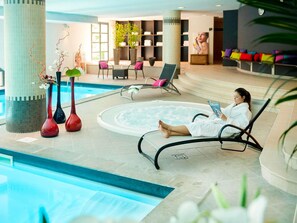 A pool area with lounge chairs, a hot tub, and decorative vases.